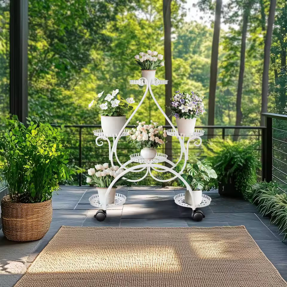 White 6-tier metal plant stand on wheels displaying potted flowers on an outdoor patio.