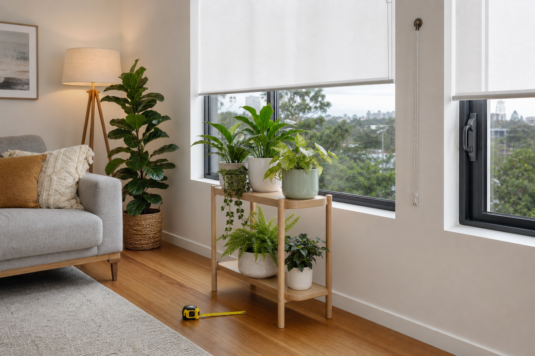 Wooden plant stand beside a window with roller blinds and a tape measure on the floor