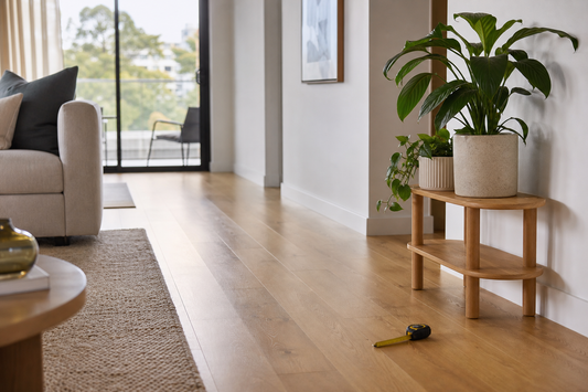 Wooden plant stand beside a clear living room walkway with a tape measure on the floor
