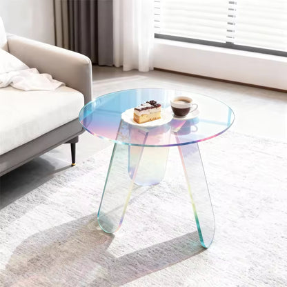 Round iridescent acrylic side table holding cake and coffee next to a sofa in a bright room.