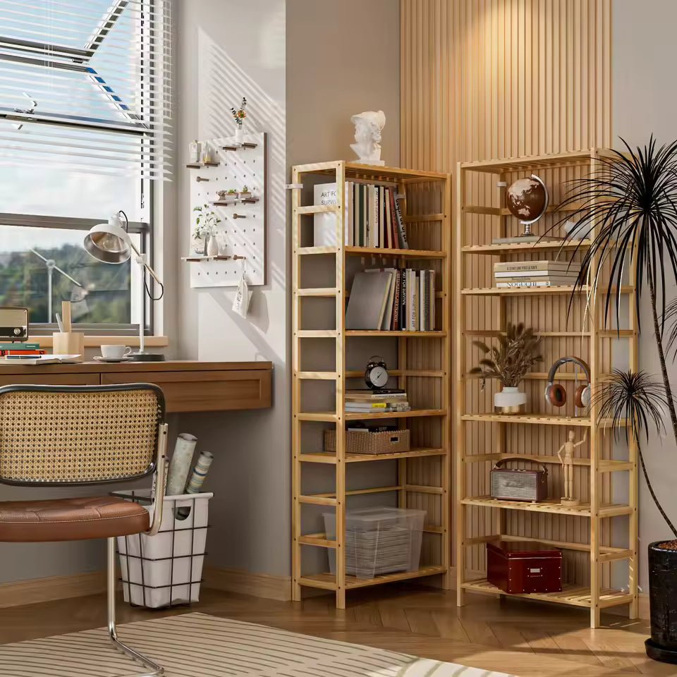 Two tall wooden bamboo bookshelves with books and decor standing next to a home office desk setup.