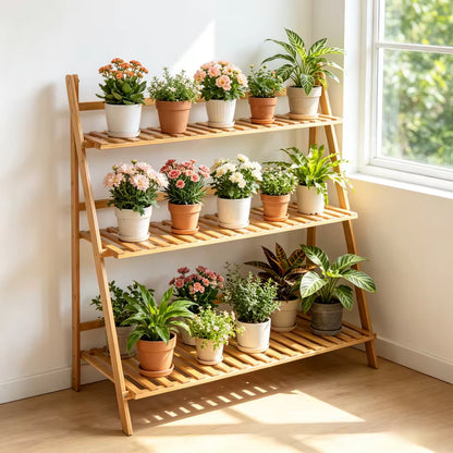 Three-tier bamboo plant stand filled with various potted flowers and houseplants near a window.