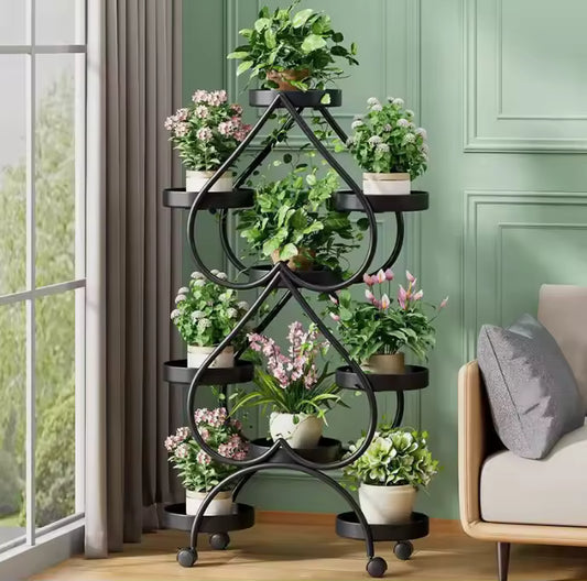 Black heart-shaped metal plant stand on wheels displaying multiple potted plants in a living room.