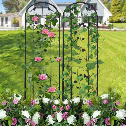 Two arched black metal garden trellis panels with climbing vines and pink flowers on a green lawn.