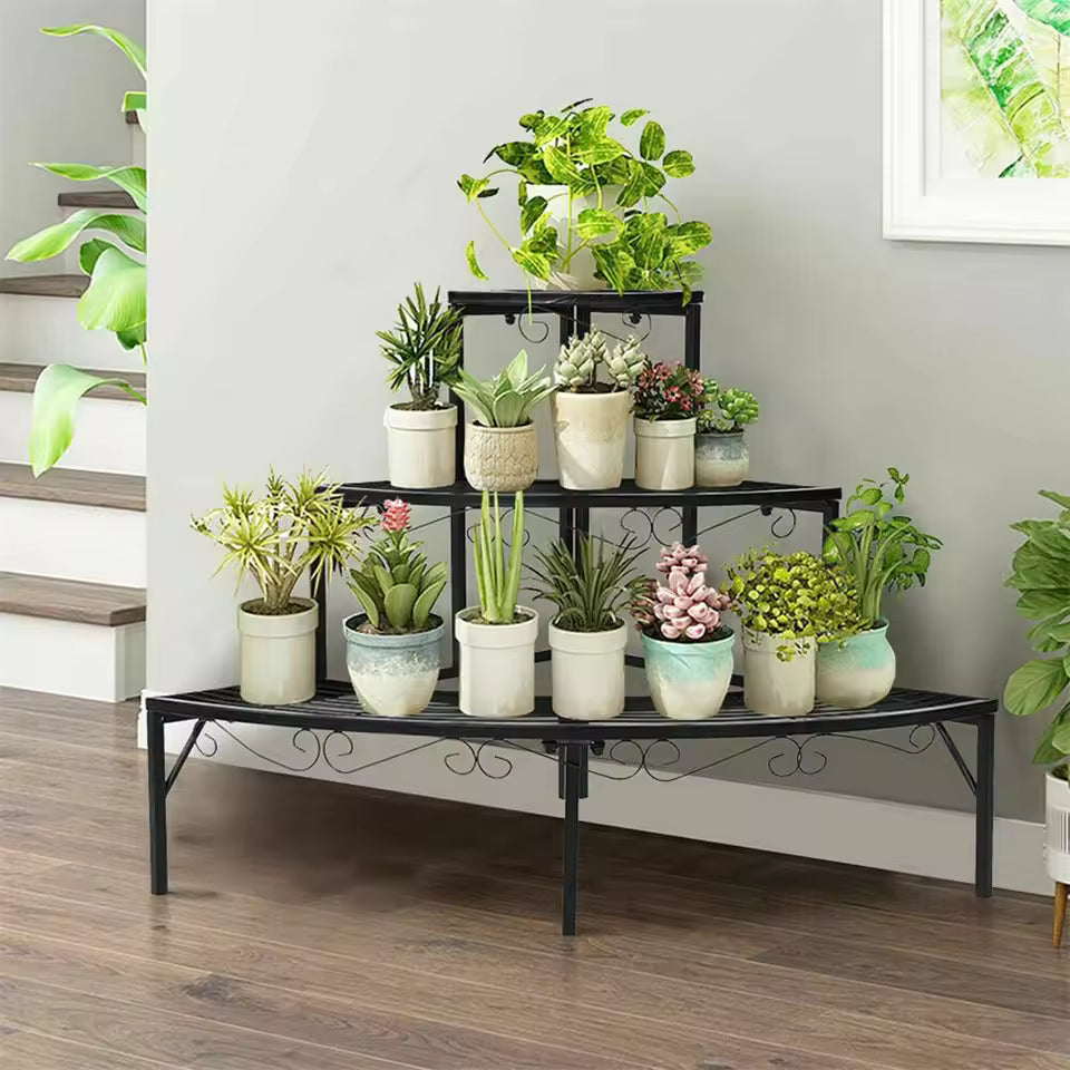 Black 3-tier metal quarter-round corner plant stand holding various potted plants indoors.