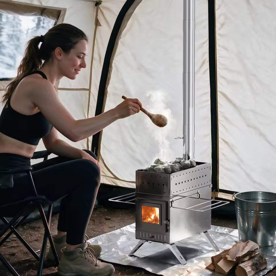 Woman sitting in a tent ladling water over sauna stones on a portable stainless steel wood stove.