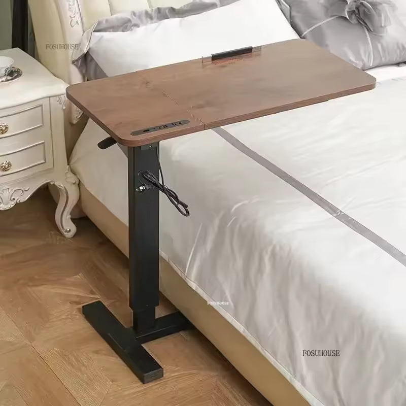 Adjustable wooden mobile overbed laptop desk positioned over a white-sheeted bed.