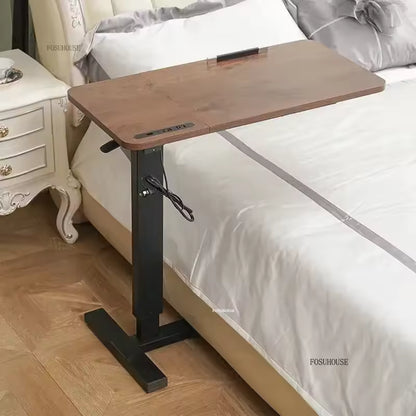 Adjustable wooden mobile overbed laptop desk positioned over a white-sheeted bed.