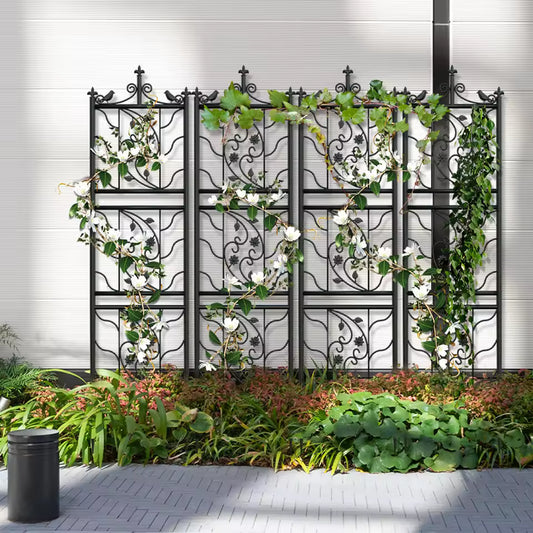Black metal lattice garden trellis panels with decorative scrollwork and climbing vines with white flowers.