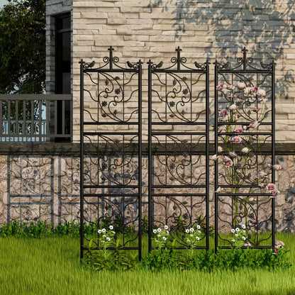 Black metal decorative garden trellis panels set on a lawn in front of a stone wall.