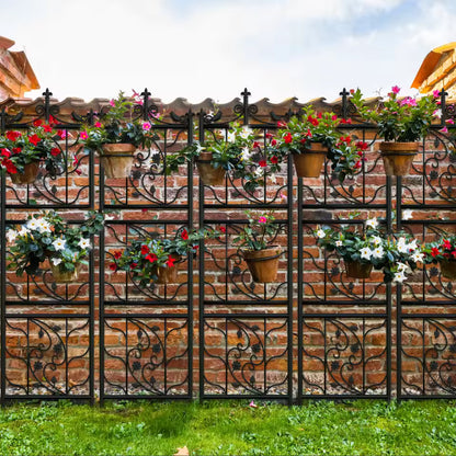 Decorative black metal lattice trellis panels holding potted flowering plants against a brick wall.