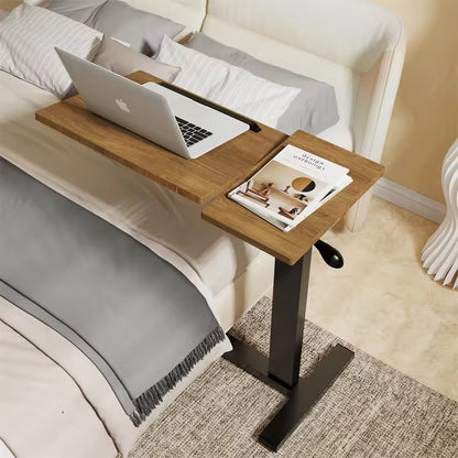 Adjustable wood over-bed desk with a laptop and magazine, set next to a white upholstered bed.