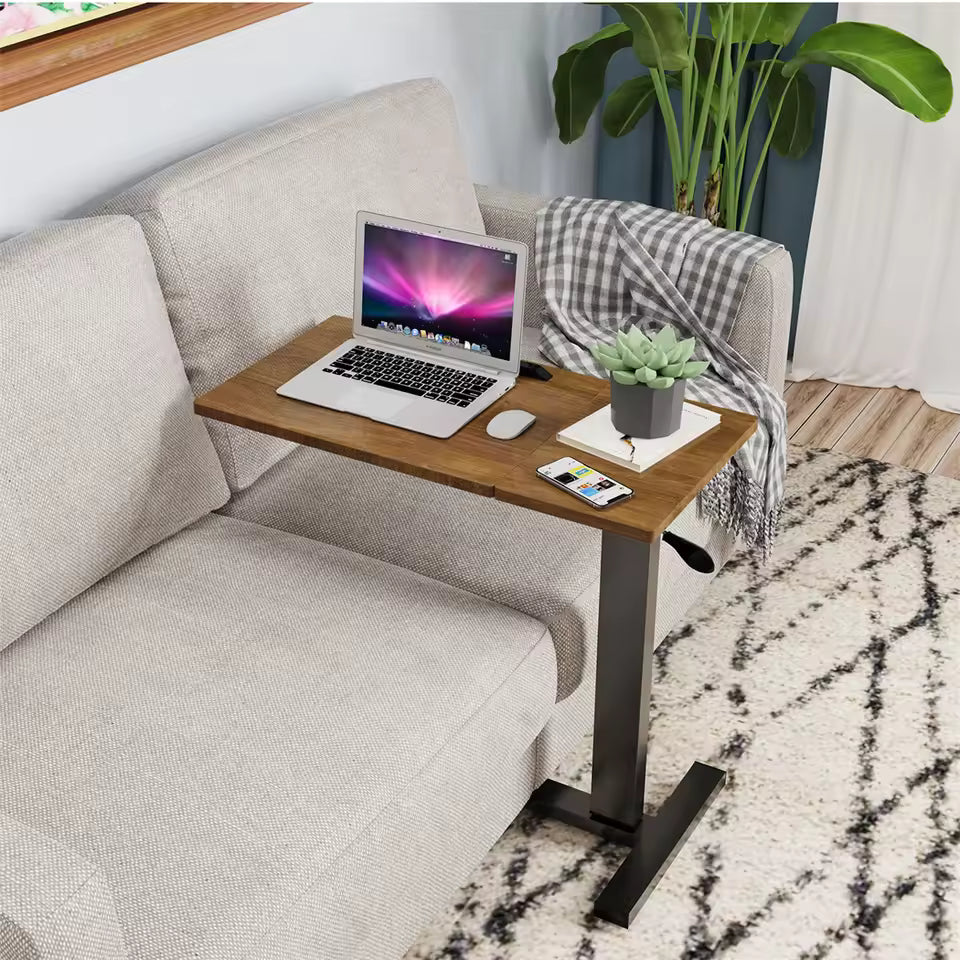 Adjustable wooden C-shaped side table with a laptop set up over a beige couch.