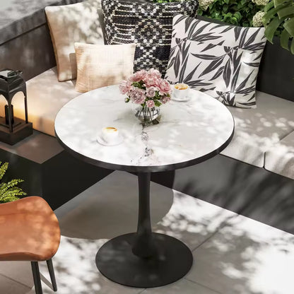 Round white marble top pedestal table set with flowers and coffee cups in an outdoor seating area.