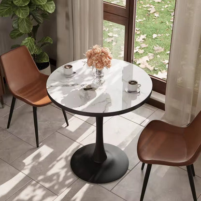 Round marble-top dining table with a black tulip base, set between two brown leather chairs near a window.