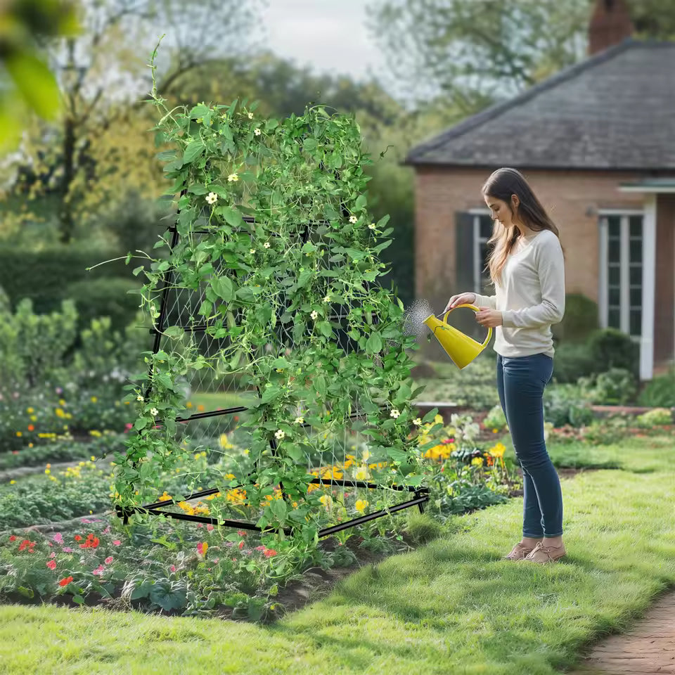 Woman watering a vine-covered metal A-frame garden trellis outdoors with a yellow can.