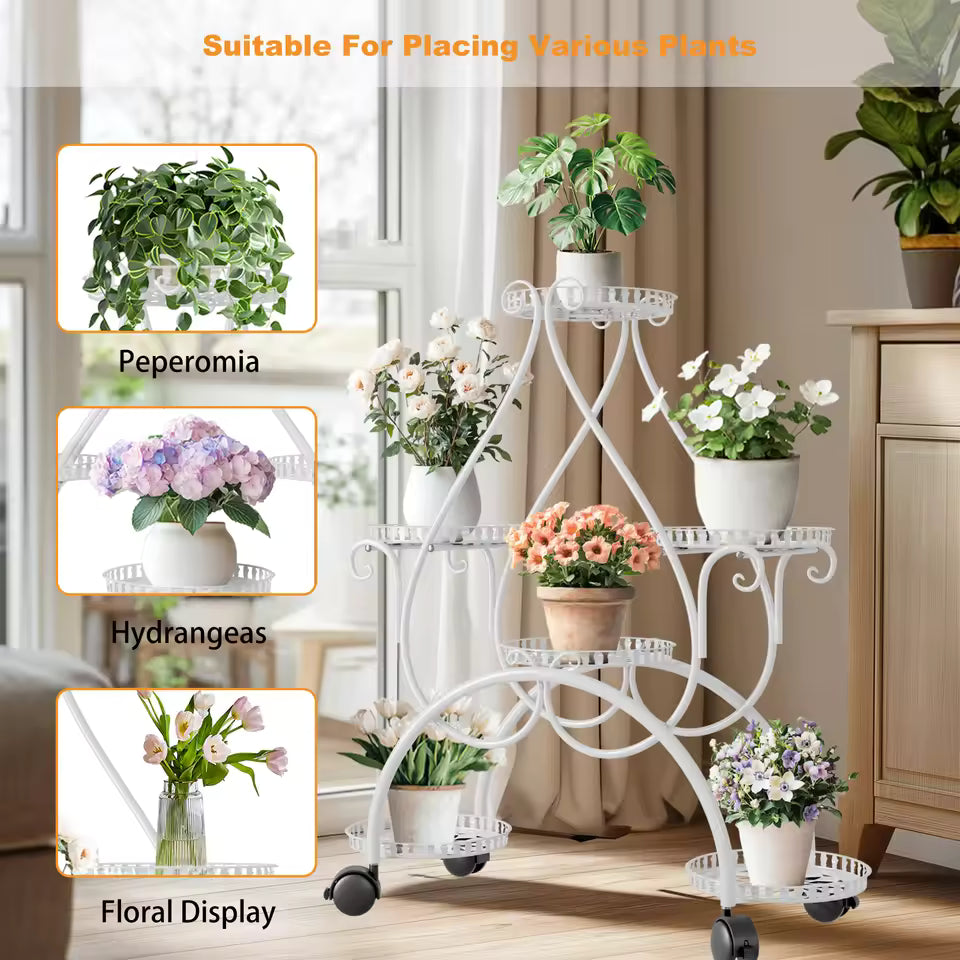 White multi-tiered metal plant stand on wheels holding potted flowers indoors.