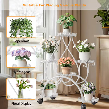 White multi-tiered metal plant stand on wheels holding potted flowers indoors.