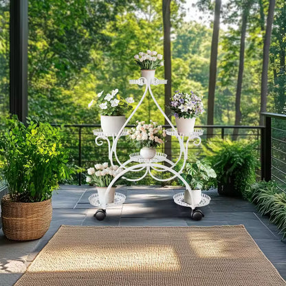 White 6-tier metal plant stand on wheels displaying potted flowers on an outdoor patio.