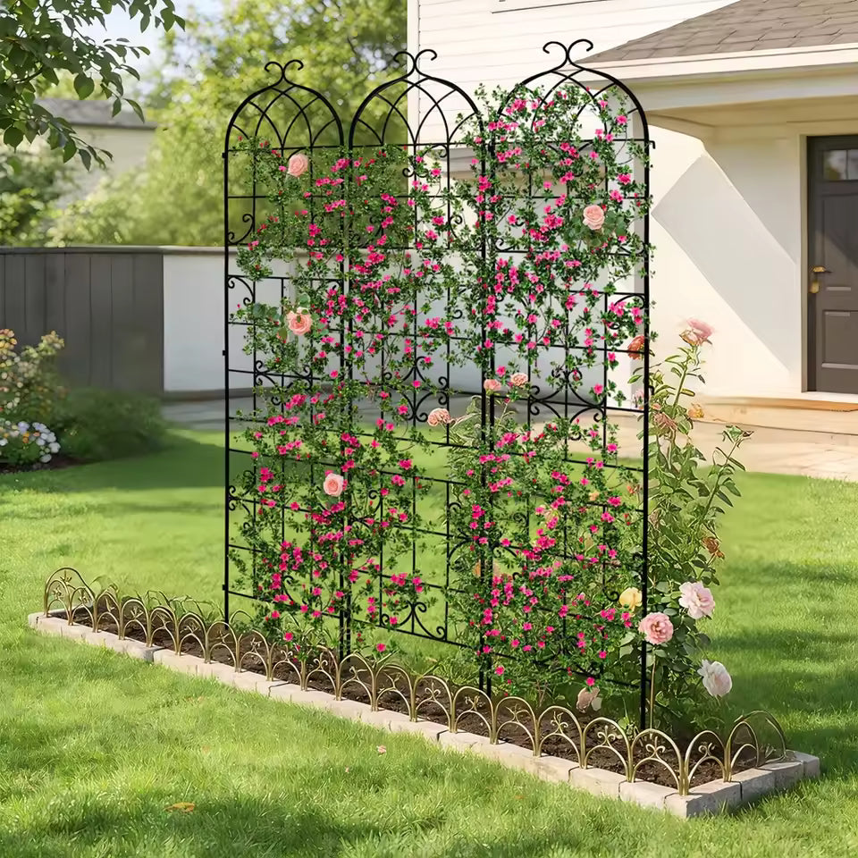 Three-panel black metal garden trellis screen covered in pink climbing roses in a backyard.