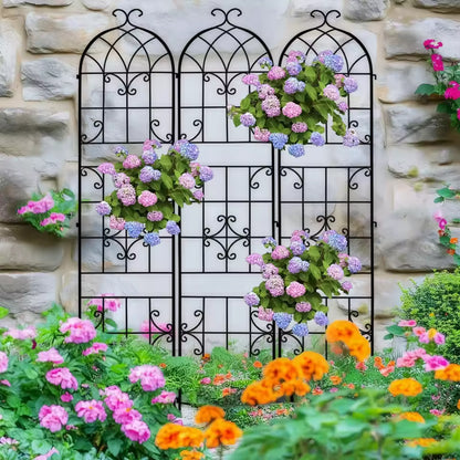 Black arched metal garden trellis panels adorned with colorful flowers against a stone wall.
