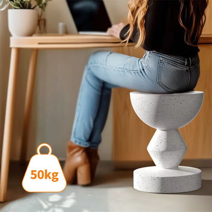 Woman sitting on a white speckled concrete geometric accent stool at a desk.