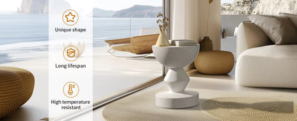 Modern speckled concrete accent side table with a geometric, sculptural base placed near a window.