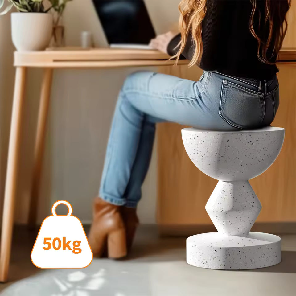 Woman sitting at a desk on a white sculpted concrete accent stool, with 50kg capacity icon.