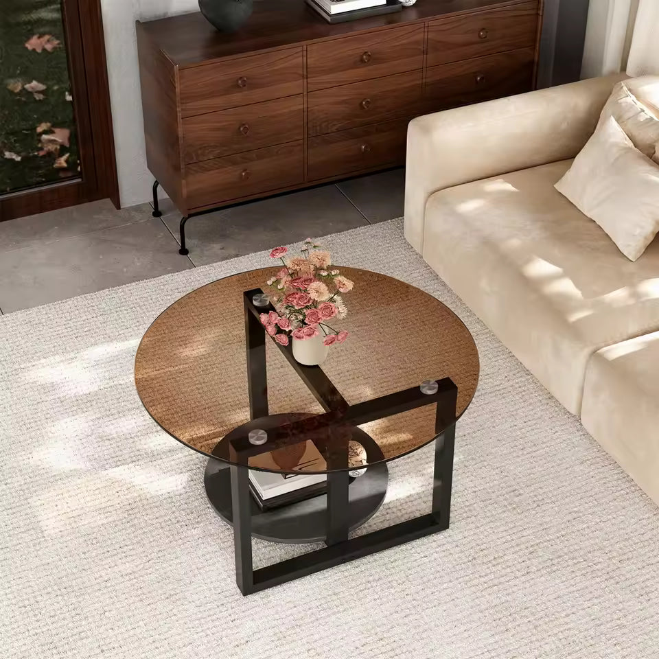 Round amber-tinted glass coffee table with black metal legs and bottom shelf in a modern living room.