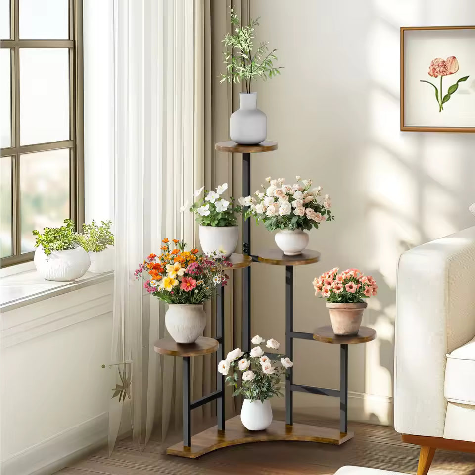Multi-tiered corner plant stand with round shelves holding potted flowers indoors.