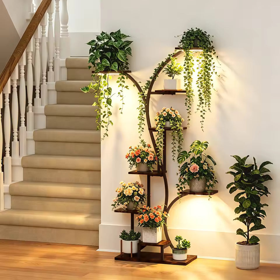 Curved multi-tiered plant stand with grow lights displaying potted plants and flowers by a staircase.
