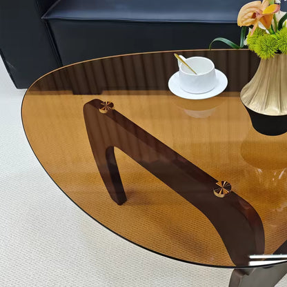 Mid-century modern coffee table with an amber glass top, dark wood legs, a teacup, and a flower vase.