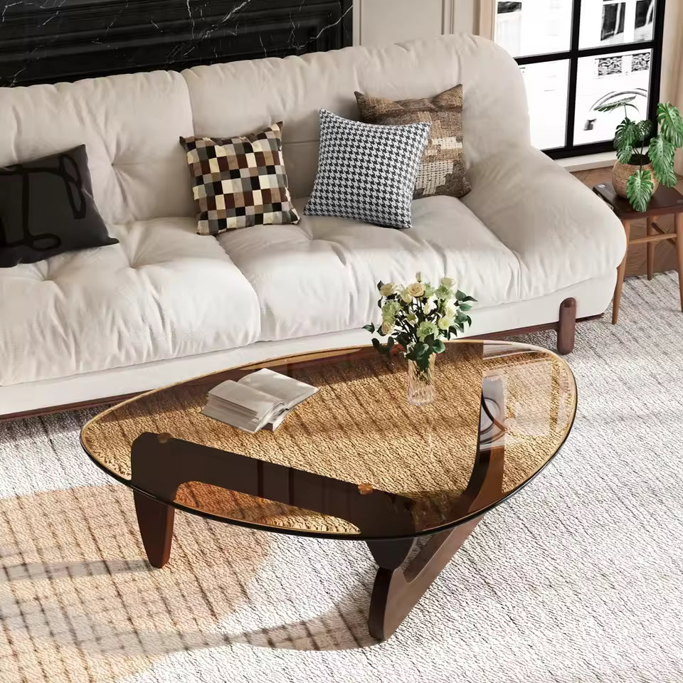Mid-century triangular amber glass coffee table with a dark wooden frame in a modern living room.