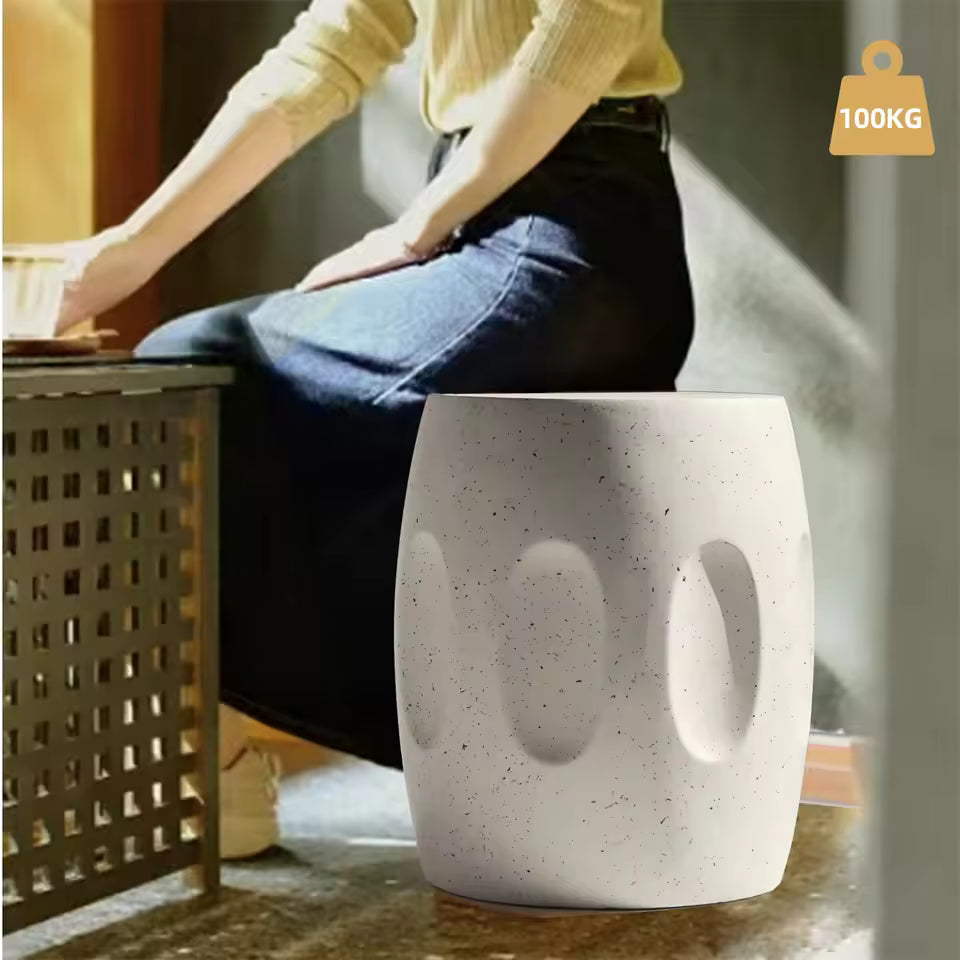 Person seated next to a white barrel-shaped concrete garden stool, featuring a 100KG capacity icon.
