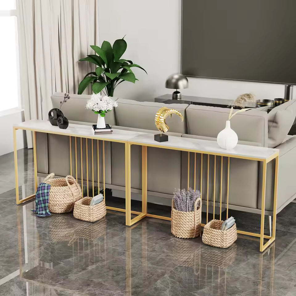 Long white console table with gold metal legs behind a sofa, styled with decor and floor baskets.