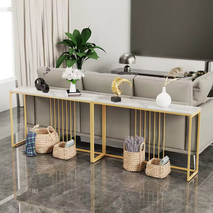 Long white console table with gold metal legs behind a sofa, styled with decor and floor baskets.