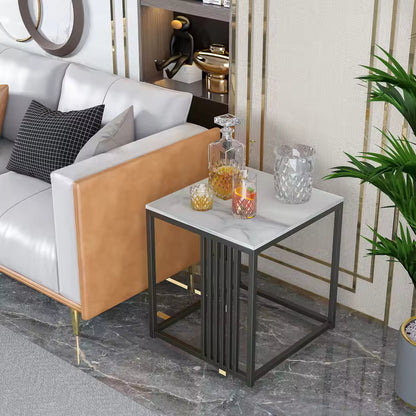 White marble top side table with a dark metal frame, holding glassware next to a sofa.