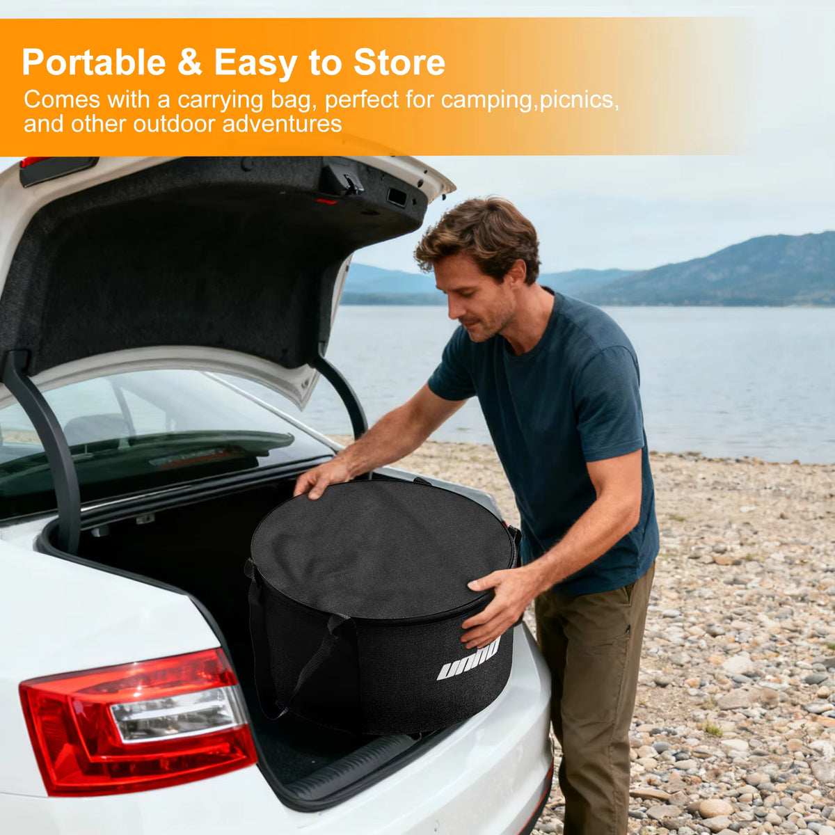 Man placing a black round carrying bag with a fire pit into a car trunk at a lake.